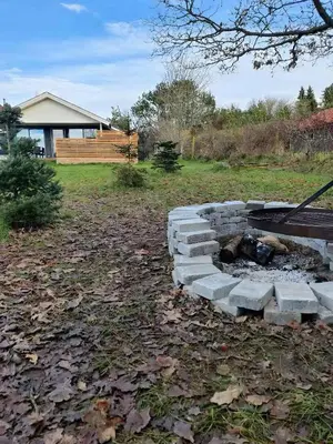 a brick fire pit in the middle of a yard at Peaceful Holiday Home With Pool Summer And Spa in Farsø