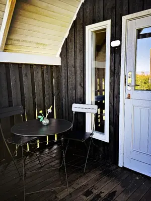 a table and chairs on a porch with a door at Bovbjerg Camping in Lemvig