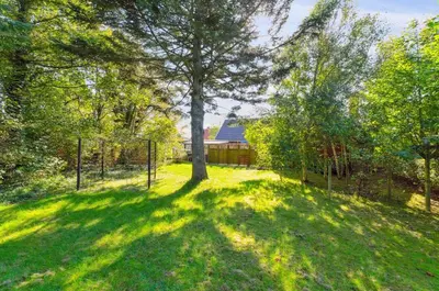a yard with a fence and a tree in the grass at Villa With Three Bedrooms in Vemb