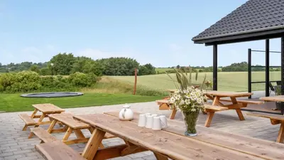 a wooden picnic table with flowers on a patio at Villavilla 546 - Hostrup Strand, Limfjorden in Spottrup