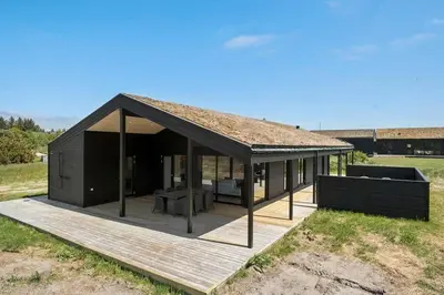a large black house with a deck in a field at BL1150-Saltum-Tolhoj-46 in Saltum