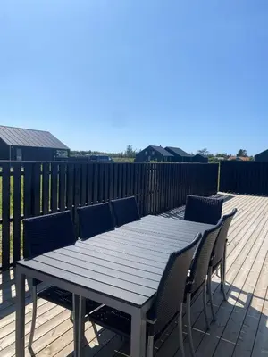 a wooden table and chairs on a deck at Luxury cottage close to the beach in Løkken