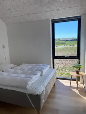 a bedroom with a bed and a large window at Luxury cottage close to the beach in Løkken