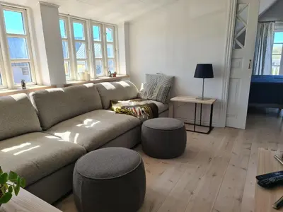a living room with a couch and some windows at Strandhuset in Agger
