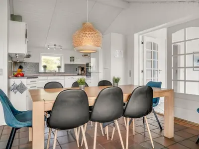 a kitchen and dining room with a wooden table and chairs at Holiday Home Nimrod - 70m from the sea by Interhome in Thisted