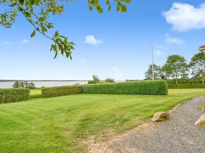 a large grassy field with hedges in a park at Holiday Home Erja - 300m to the fjord by Interhome in Roslev