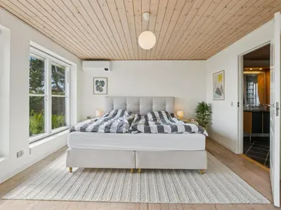a bedroom with a large bed with a wooden ceiling at Holiday Home Fridhild - 150m to the fjord by Interhome in Redsted