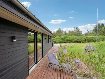 a wooden deck with a bench on the side of a house at Holiday Home Muriel - 1-6km from the sea by Interhome in Blokhus