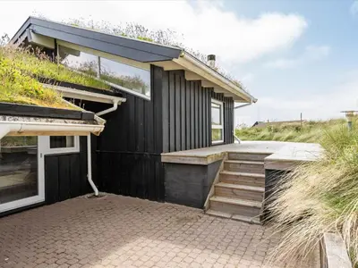 a black house with a staircase leading up to it at Holiday Home Osfrid - 175m from the sea by Interhome in Blokhus