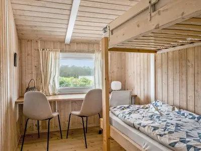 a bedroom with a bed and a desk and chairs at Holiday Home Osfrid - 175m from the sea by Interhome in Blokhus