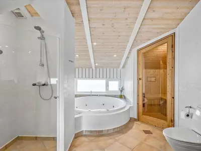 a white bathroom with a tub and a toilet at Holiday Home Osfrid - 175m from the sea by Interhome in Blokhus