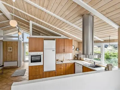 a kitchen with wooden cabinets and white appliances at Holiday Home Osfrid - 175m from the sea by Interhome in Blokhus