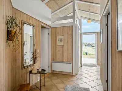 a hallway with wood paneling and a door with a table at Holiday Home Osfrid - 175m from the sea by Interhome in Blokhus