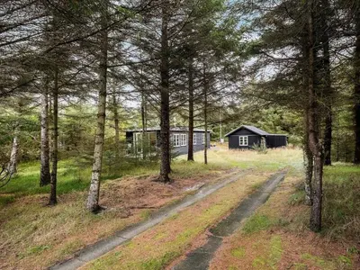 a dirt road leading to a cabin in the woods at Holiday Home Patti - 700m from the sea by Interhome in Blokhus