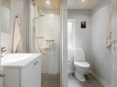 a white bathroom with a toilet and a shower at Holiday Home Patti - 700m from the sea by Interhome in Blokhus