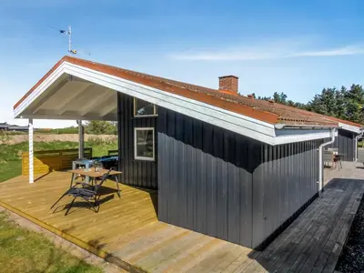 a house with a deck with a table and a roof at Holiday Home Peder - 700m from the sea by Interhome in Løkken