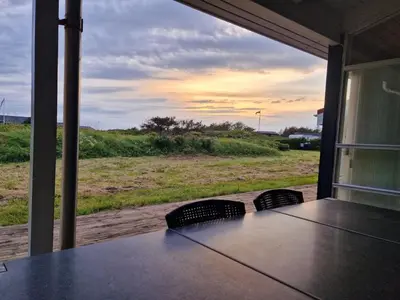 a table with chairs and a view of a field at Holiday Home Peder - 700m from the sea by Interhome in Løkken