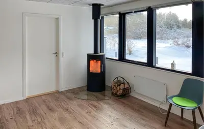 a room with a fireplace and a chair and windows at 3 Bedroom Stunning Home In Struer in Struer