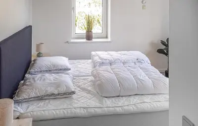 a bed with white sheets and pillows in a bedroom at 4 Bedroom Beautiful Home In Farsø in Farsø