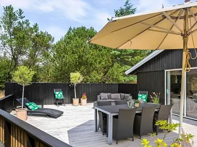 a patio with a table and an umbrella at 4 star holiday home in Blokhus in Blokhus