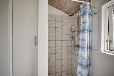 a bathroom with a shower with a blue shower curtain at Peaceful Base Near Beach And Nature in Saltum