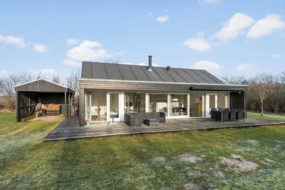 a house with a wooden deck in a field at JB405-Brovst-Kronvildtvej-37 in Tranum Strand