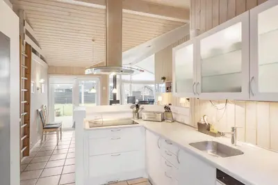 a kitchen with white cabinets and a large window at BL1143-Blokhus-Engen-1 in Blokhus