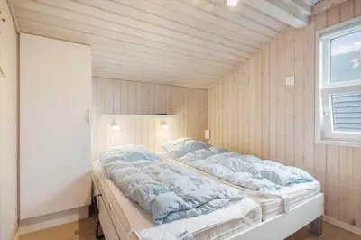 a large bed in a room with a wooden ceiling at BL1143-Blokhus-Engen-1 in Blokhus