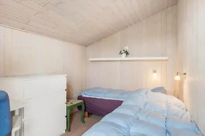 a small bedroom with a bed and a shelf at BL1143-Blokhus-Engen-1 in Blokhus