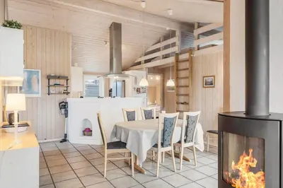 a dining room with a table and a fireplace at BL1143-Blokhus-Engen-1 in Blokhus