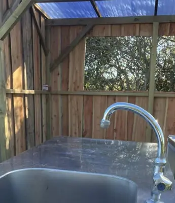 a kitchen sink with aaucet in a wooden shed at Stenbækgård - Farm Glamping in Højslev