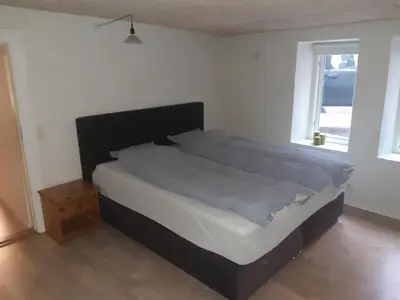 a large bed in a bedroom with a window at Stor lejlighed ved togstation in Viborg
