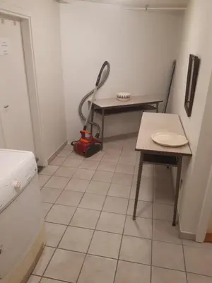 a kitchen with a table and a vacuum in a room at Stor lejlighed ved togstation in Viborg