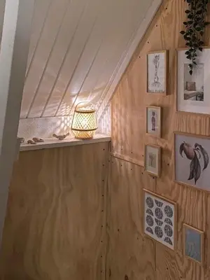 a room with a lamp on a wall with pictures at Cosy Little Wooden House On Natural Grounds in Vestervig