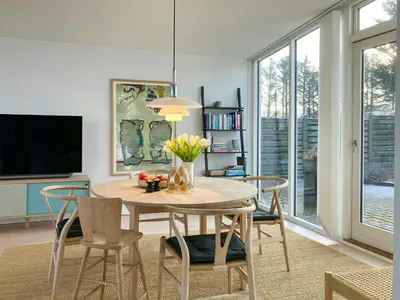 a dining room with a table with chairs and a tv at Restored Fisherman's House On Cliff In Thy in Hanstholm