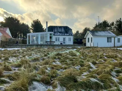 a white house with a field of grass at Restored Fisherman's House On Cliff In Thy in Hanstholm