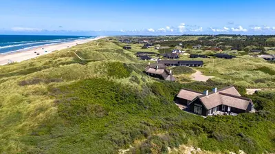 an aerial view of a house on a hill next to the beach at Thatched House At First Dune Row In Blokhus in Blokhus