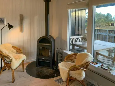 a living room with two chairs and a wood stove at Holiday Home By The North Sea Dunes In Rødhus in Pandrup