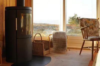 a fireplace in a living room with a chair and a window at Holiday Home With Private Beach Trail And Sea View in Trend