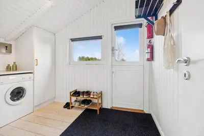 a laundry room with a washing machine and a door at BL1155-Blokhus-Berberisvej-74 in Blokhus
