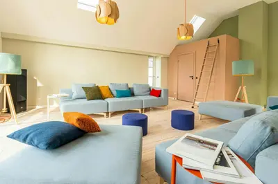 a living room with blue couches and a ladder at Historic Farm And Surf Shack At Cold Hawaii in Thisted