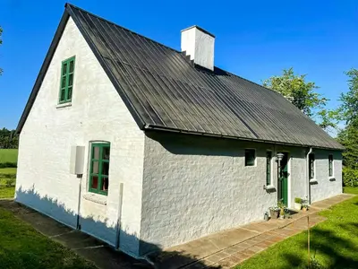 a white barn with a black roof and green windows at Historic House From 1887 Near Nationalpark Thy