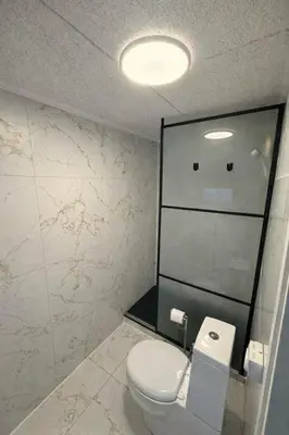 a bathroom with a toilet and a glass wall at Hel hus i rolig by in Birkelse