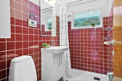 a red tiled bathroom with a toilet and a sink at BL1154-Blokhus-Kornblomstvej-22 in Blokhus