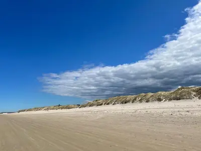 a sandy beach with a blue sky and clouds at Søndergade 21, Lejl 3 in Løkken