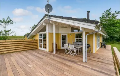 a house with a wooden deck with a table at Holiday Home Hurup Thy With A Fireplace 06 in Heltborg