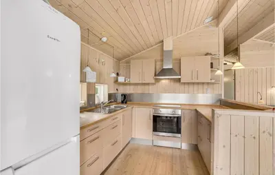 a kitchen with wooden cabinets and a sink and a stove at Holiday Home Hurup Thy With A Fireplace 06 in Heltborg