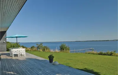 a patio with a table and an umbrella and the water at Holiday Home Roslev With A Fireplace 01 in Roslev