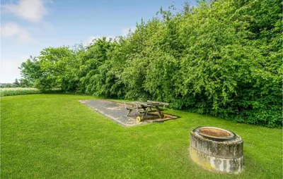 a picnic table and a barrel in the grass at Nørklit in Frøstrup
