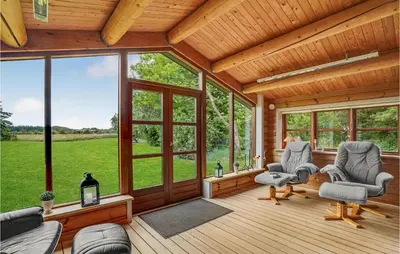 a screened in porch with chairs and windows at Nørklit in Frøstrup